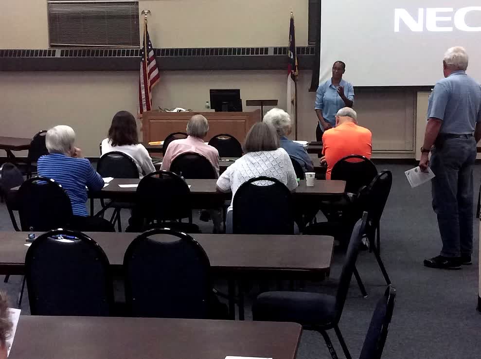 Community meeting-room talk with attendees at tables